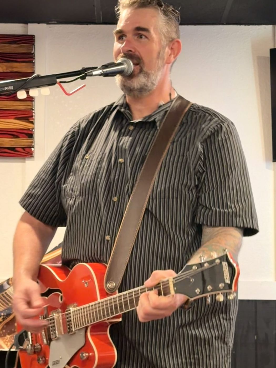 Randy singing into a microphone while playing an orange electric guitar