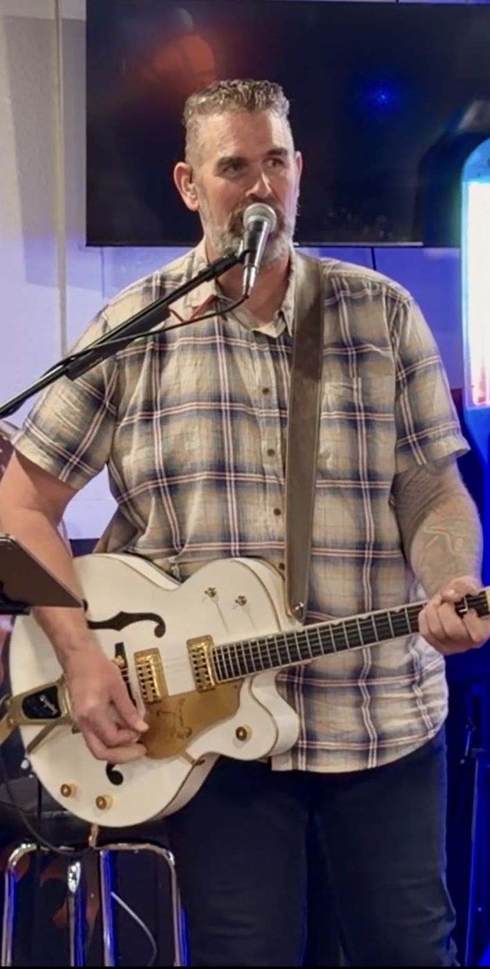 Randy performing with a white hollow-body guitar